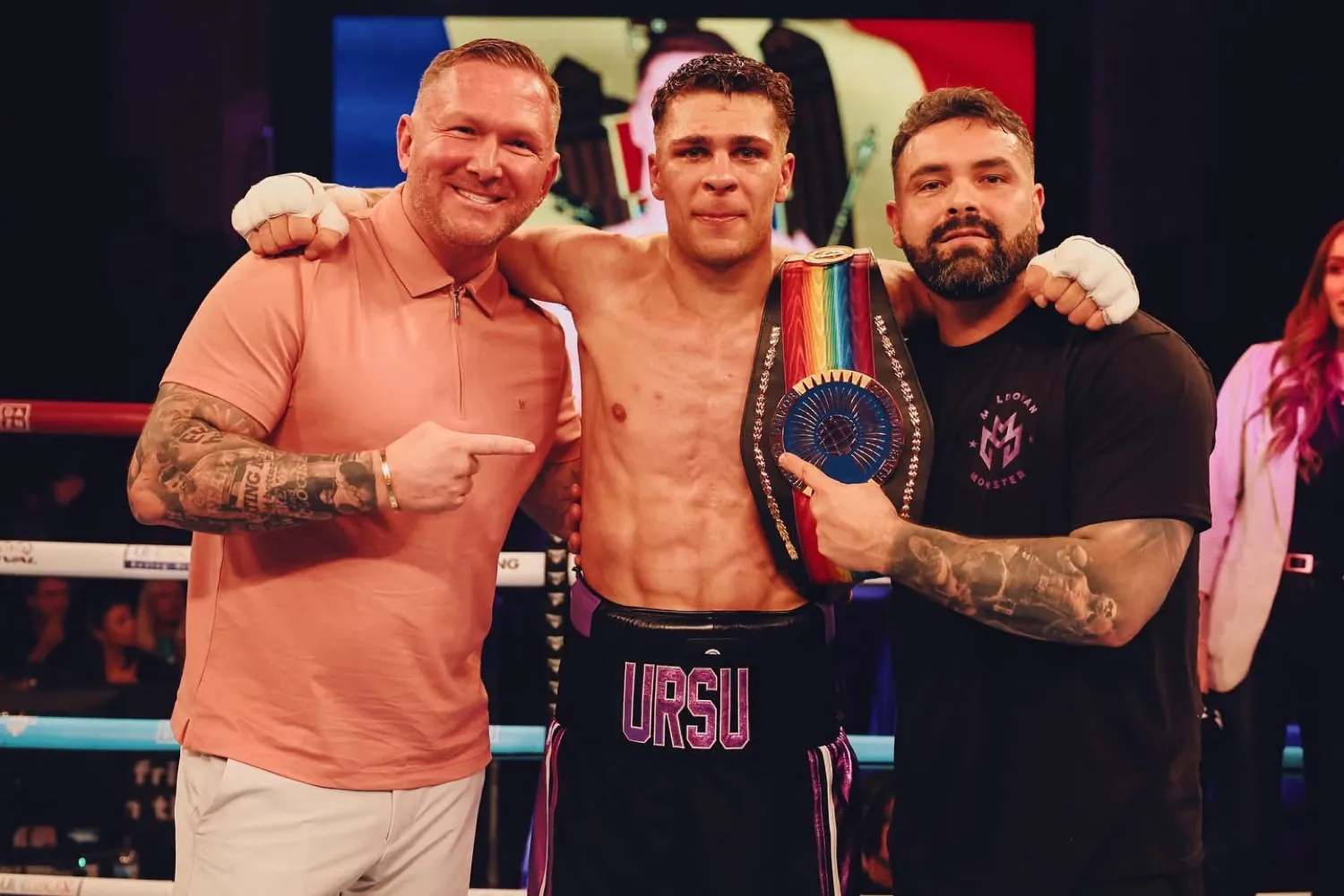 Constantin Ursu with a championship belt, flanked by two team members
